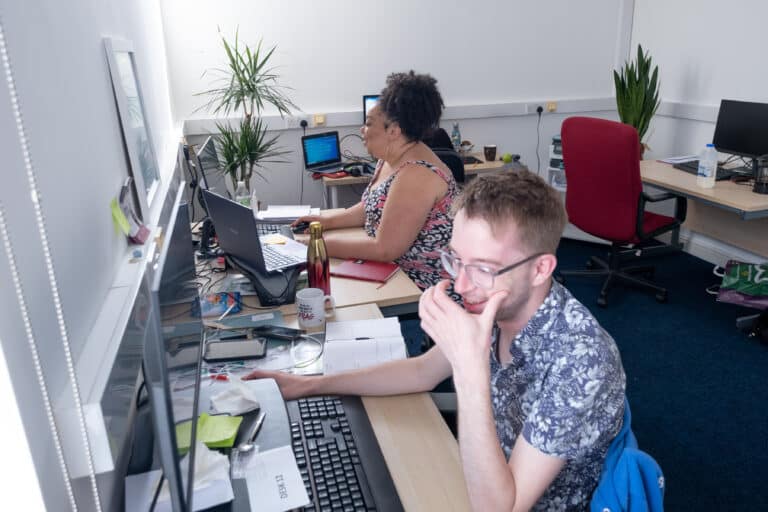 Two people working at their computers in their office